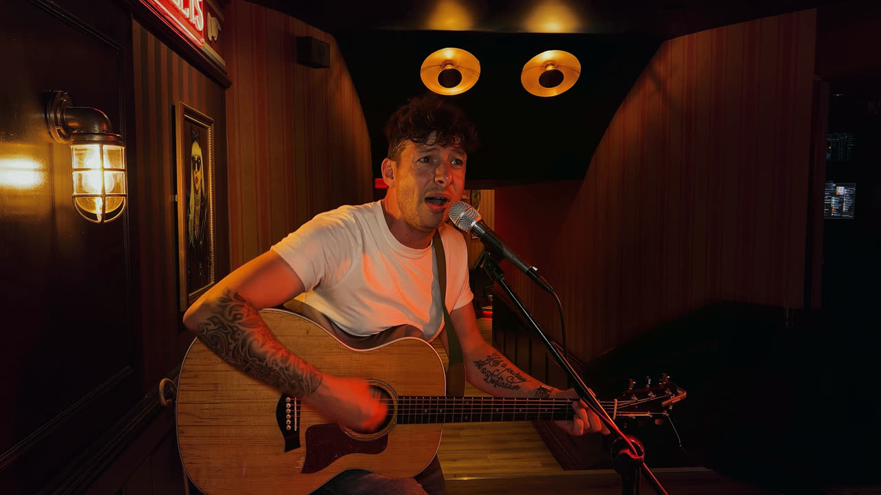 The same pub frame on the clean automatic grade — the singer lit naturally, the dark room held honest